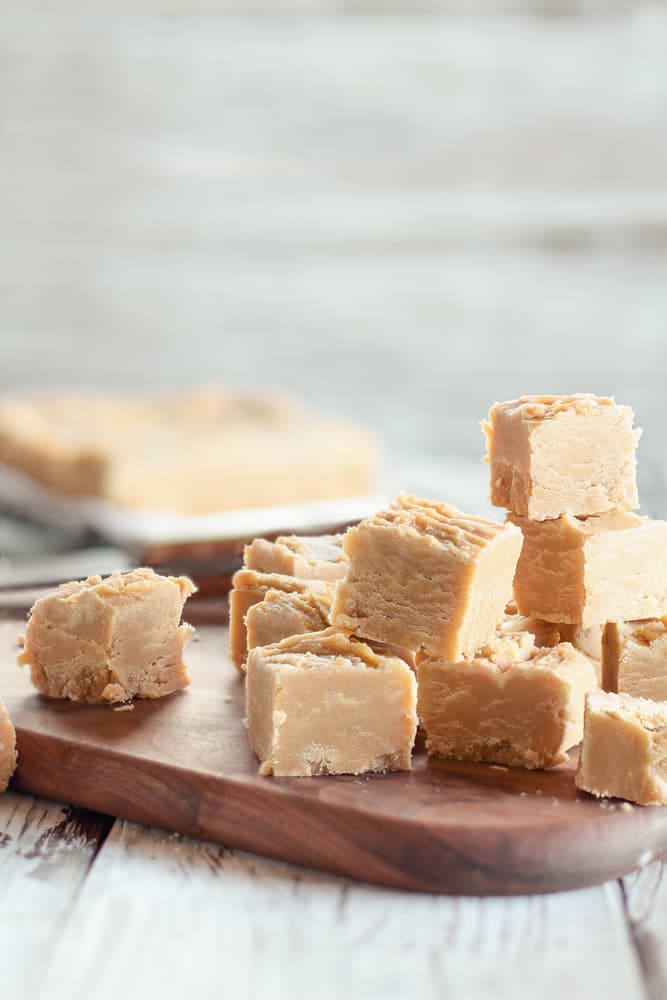 Golden peanut cannabutter fudge squares atop a wood slab.